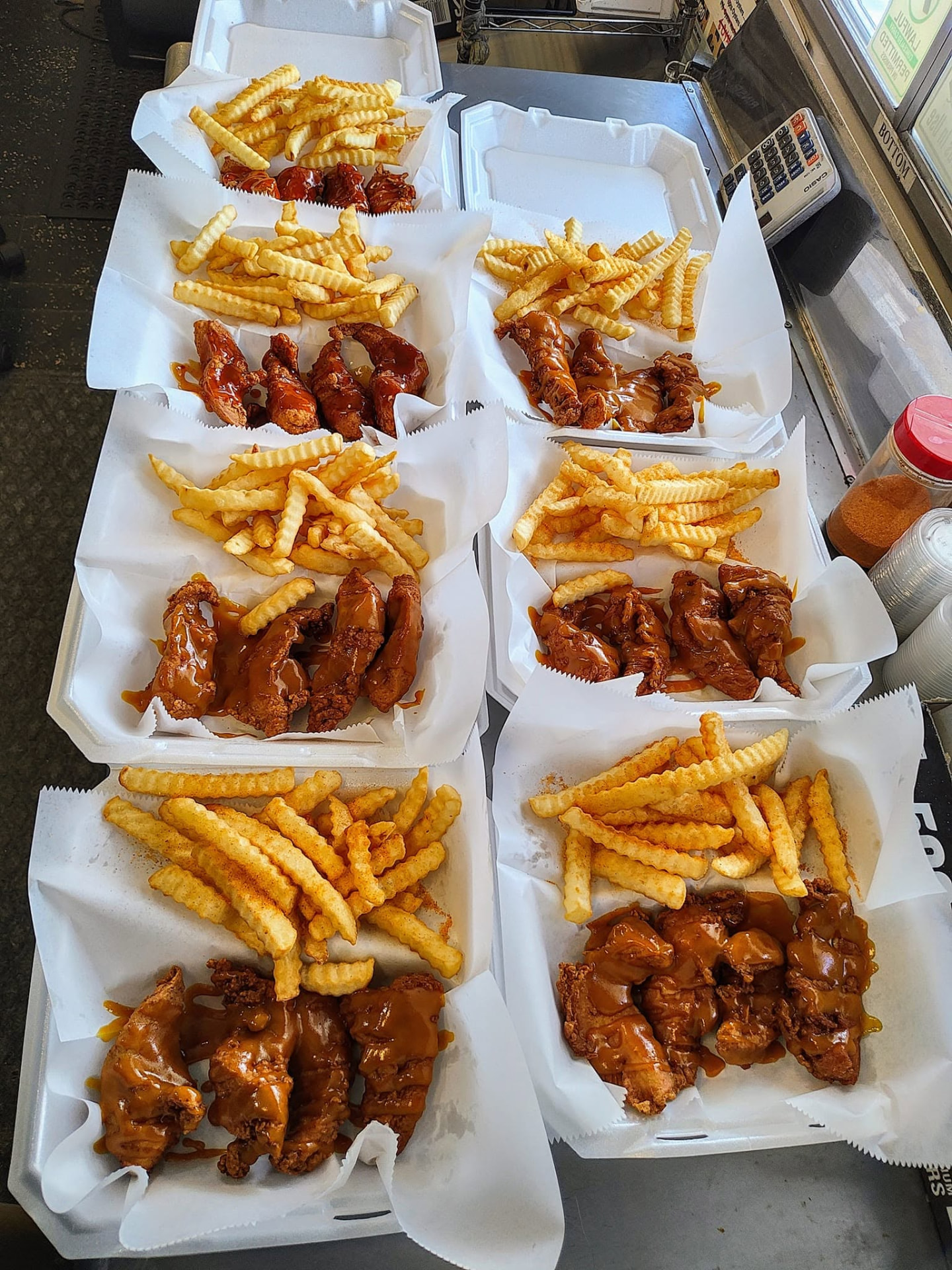 Six boxes of saucy fried chicken tenders with seasoned crinkle fries