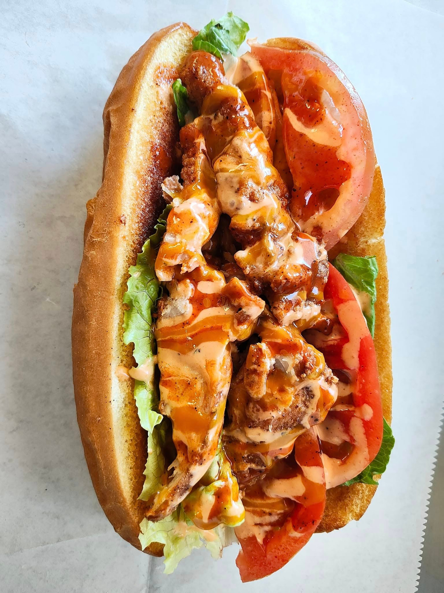 Fried chicken po' boy with lettuce, tomato and double sauce drizzle