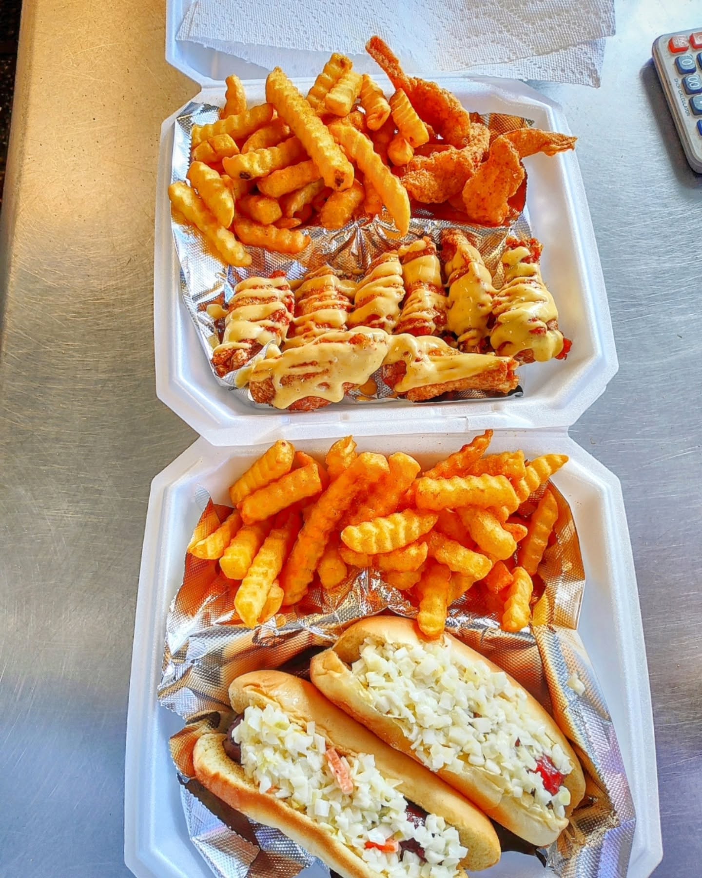Sauced wings, fried shrimp, crinkle fries and two slaw dogs in takeout boxes
