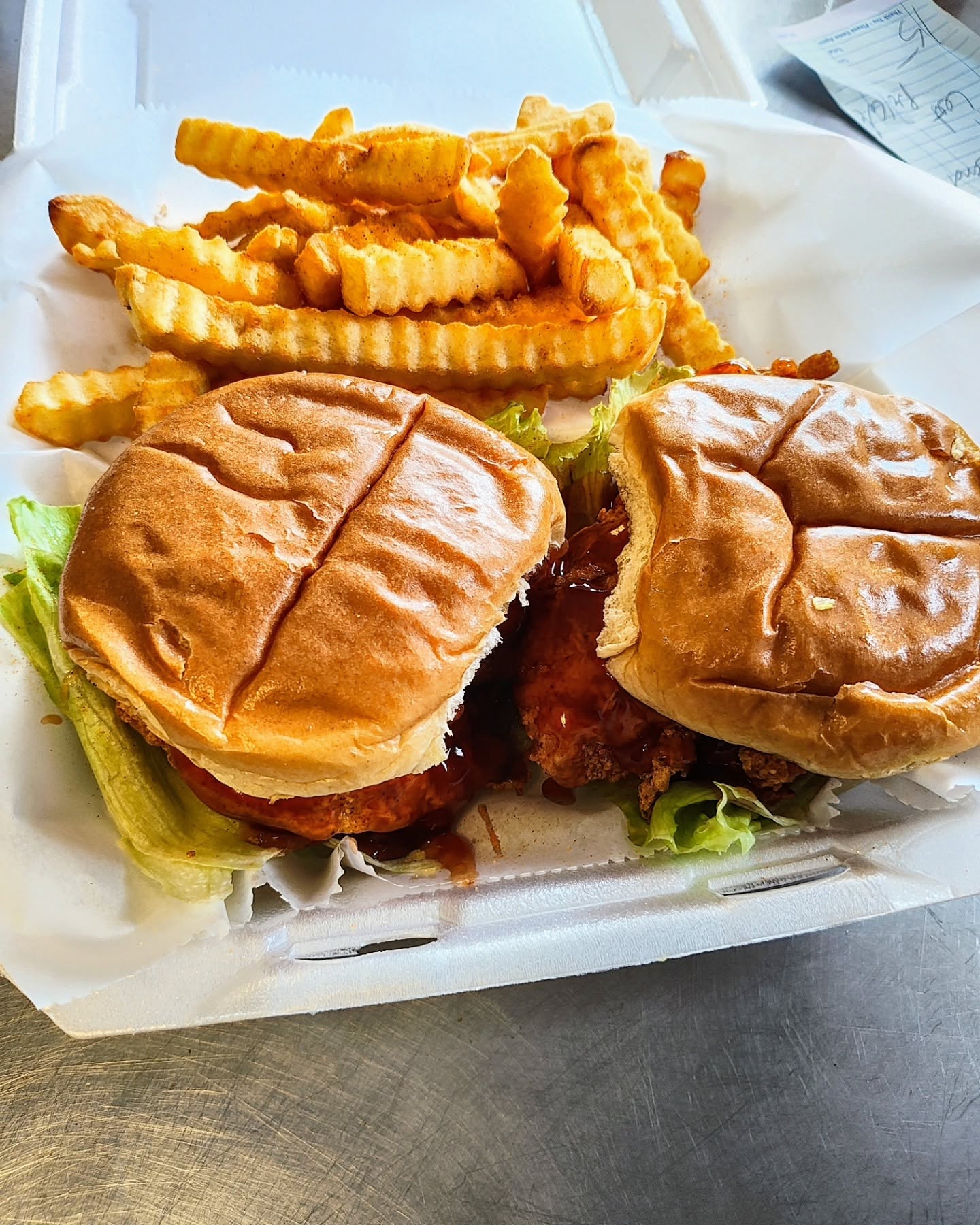 Two saucy fried chicken sandwiches with seasoned crinkle fries